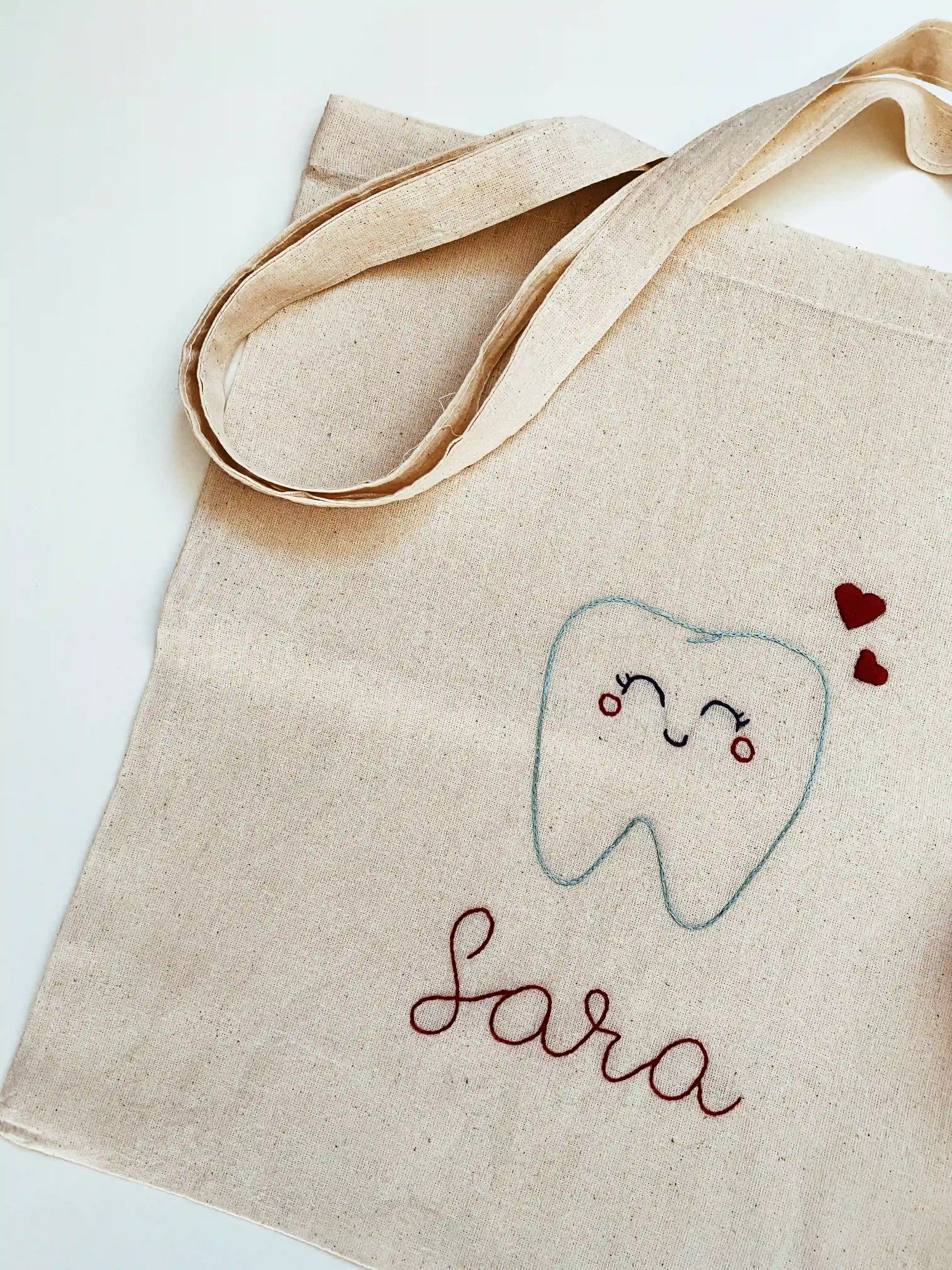 Canvas tote embroidered with a smiling tooth and the name Sara